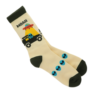 A pair of cream-colored crew socks with dark green heels, toes, and cuffs. The front sock features a cartoon graphic of a black vehicle with a blue skull inside, a red UFO, and the text 'MOAB' in black.