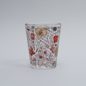 Clear glass tumbler with floral pattern on a white background
