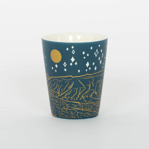 Teal mug with gold and white designs on a white background