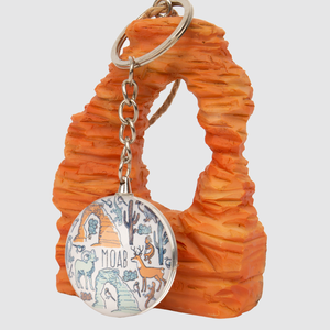 Keychain with a circular pendant featuring illustrations of animals and text, attached to an orange rock-like object.