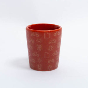 Red ceramic cup with white illustrations on a white background