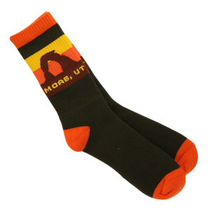 A pair of crew socks in black with bright orange toe and heel accents, a yellow and orange striped cuff, and a brown graphic with the text 'MOAB, UT' on a white background.