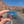 Hand holding the Arches Bigfoot and raptor enamel pin on a road through the Moab red rock cliffs.