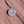 Round white and maroon Arches National Park enamel pin lettered with 1929 and Delicate Arch, lying on red sandstone in Moab, Utah.