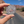 Hand holding the Arches National Park 1929 medallion enamel pin on a road through the Moab red rock cliffs.