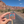 Hand holding the Arches National Park pink sky enamel pin on a road through the Moab red rock cliffs.