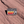 Rectangular Arches National Park Utah enamel pin with retro orange and red stripes and Delicate Arch, lying on red sandstone in Moab, Utah.