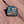 Die cut Arches enamel pin with Delicate Arch under a blue and pink starry sky, lying on red sandstone in Moab, Utah.