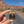 Hand holding the Canyonlands Island in the Sky enamel pin on a road through the Moab red rock cliffs.
