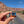 Hand holding the Moab trail sign lapel pin on a road through the Moab red rock cliffs.