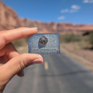 Back of the Moab Utah geometric sunset enamel pin showing the rubber clutch and simplymoab.com stamp.