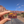 Hand holding the Moab Utah geometric sunset enamel pin on a road through the Moab red rock cliffs.