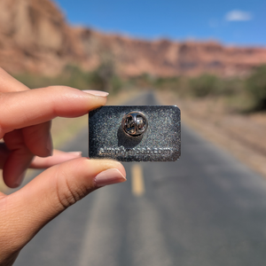Back of the Moab Utah retro stripes enamel pin showing the rubber clutch and simplymoab.com stamp.