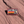 Rectangular Moab Utah enamel pin with retro sunset stripes and a Delicate Arch silhouette, lying on red sandstone in Moab, Utah.