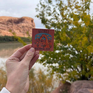 Hand holding the Simply Moab Arches Dirt Scenic Magnet by the Colorado River near Moab