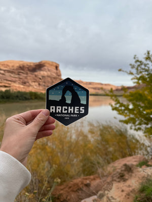 Hand holding the Simply Moab Arches Hexagon Night Sky Sticker by the Colorado River near Moab